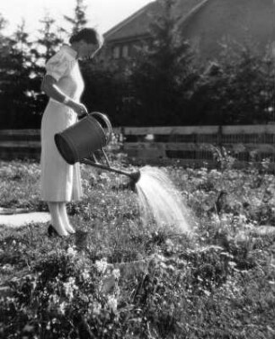 Garten. Frau beim Gießen mit einer Gießkanne