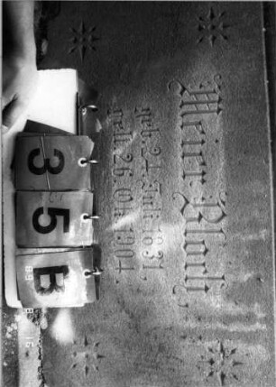 Grabstein 35 (Index: 100086668) Material: Sandstein mit zwei weißen Marmorplatten Zustand: leicht verwittert Maße HxBxT: 190x64x29 cm Beschreibung: Stele, getreppter Sockel, Giebel mit Akroteren, Schriftfeld rechteckig, Schrifttafel im Giebel dreieckig Symbolik: Zahnfries, Blätterfries, vier Sterne im Sockel, Palmetten als Mittelakroter: Grabstein 35B