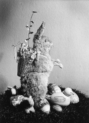Osterhasenbilder. Osterhase mit Kiepe, umgeben von Eiern, kleinem Hasen und Küken