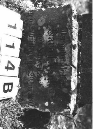 Grabstein 114 (Index: 100106426) Material: grau-schwarzer Granit, unterster Sockel Sandstein Zustand: gut Maße HxBxT: 144x37x19 cm Beschreibung: obeliskenartige Stele, getreppter Sockel: Grabstein 114B