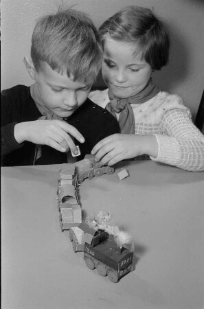 Junge Pioniere beim Basteln. Junge und Mädchen mit Spielzeugeisenbahn