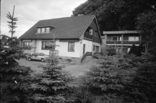 Gästehaus Seeblick: Ahrensböker Straße: Haus mit Terrasse: links davor Parkplatz mit Pkw: rechts dahinter Hotelgebäude: im Vordergrund Tannen: hinten Bäume