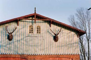 Gräberkate: Gräberkater Weg 19: traufständiges Wirtschaftsgebäude aus Backstein: südliche Giebelseite, Teilansicht: Obergeschoss mit Verbretterung, Rundbogenfenster mit Sprossen, beiderseits zwei Hirschköpfe mit Geweih, Giebelzier