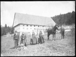 Familie vor ihrem Bauernhaus