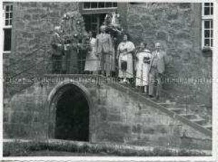 Der Direktor der Deutschen Kolonialschule in Witzenhausen vor dem Eingang in den Südflügel des Schulgebäudes umgeben von Frau und Sohn sowie weiteren Personen am Erntefest 1934