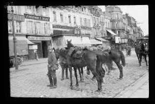Cambrai (Dep. Nord, Frankreich): Soldat mit Pickelhaube neben abgestellten Pferden auf einer Straße am Marktplatz