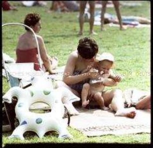Mutter füttert Kind im Freibad Pankow