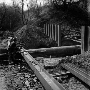 Bahnstrecke zwischen Hamburg und Lübeck: Auetal: Erneuerung der Brücke über die Aue: Spundwände: Arbeiter schweißt Rahmen für neuen Stahlbeton-Durchlass: Aue (Mühlenbach) fließt in Rohr