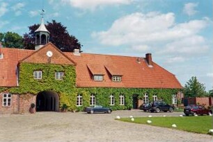 Altfresenburg: Gut: Torhaus, Teilansicht: Blick von Westen: Mittelteil mit Torduchfahrt, Zwerchhaus, in Giebel Uhr, darüber Dachreiter: rechter Gebäudeteil mit Sprossenfenstern, Tür: Kletterpflanzen