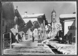 Mittenwald, Straße mit Wohn- und Geschäftshäusern an der barocken Pfarrkirche