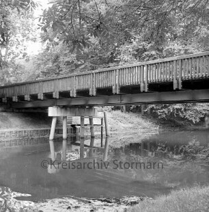 Travebrücke: Landstraße zwischen Nütschau und Schlamersdorf: Nütschauer Weg: Brückenbau: Holzbrücke auf Betonpfeilern vor Fertigstellung: darauf Baufahrzeug und Baumaterial: vorn Trave