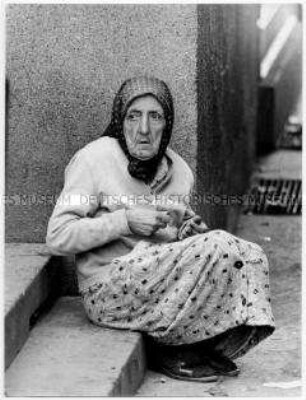 Alte Frau sitzt auf einer Treppenstufe (Altersgruppe 14-17)
