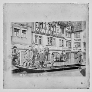Hochwasser in der Brückengasse, Personen in Schelchen und auf Stegen vor dem Cafe Quenzer, darauf Nr. 71