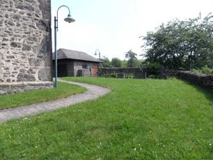 Kirchhof im Osten mit Kirchhofmauer (Wehrgang mit Steinbrüstung und Schießscharten abgetragen) in übersichtlichem Verlauf