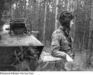 Deutschland . Truppenübungsplatz Klietz. Nationale Volksarmee - Landstreitkräfte. Soldat mit Panzerhaube, an einem Gefechtsfahrzeug lehnend