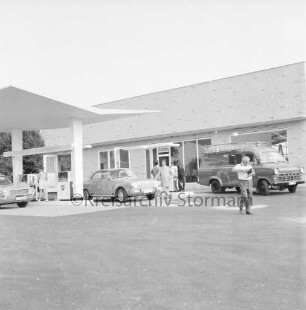 BP-Tankstelle: Hamburger Straße: Neubau: rechts Gebäude: davor Zapfsäulen mit tankenden Pkws, Kleintransporter und Personen
