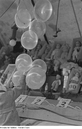 Kind an einem Losstand nach Luftballons greifend