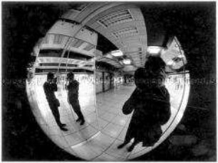 Junger Mann fotografiert in einen runden Bahnhofsspiegel (Altersgruppe 18-21)