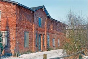 Viertbruch (25): Bauernhaus aus Backstein mit umlaufendem Gesims: Traufseite, vorne Wohntrakt mit Lisenen, Eingangstür, darüber Frontispiz, hinten ehemaliger Wirtschaftstrakt: links Giebelseite Wohntrakt [angeschnitten]: Weg, Büsche