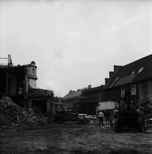 Firma Carl Hoffmann: Hindenburgstraße: Elektrohandel: Abriss des Firmengebäudes: Bauschutt mit Bretterhaufen: dazwischen Bagger und Arbeiter: hinten links Wohn- und Geschäftshaus mit Drogerie Purnhagen: rechts Wohn- und Geschäftshaus mit Haushaltswarenhandlung Otto Möller: dazwischen Marktplatz mit Stadthaus, eingerüstetem Postgebäude und Wohnhaus an Hagenstraße