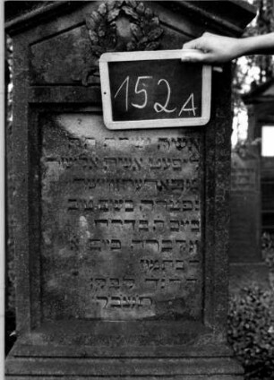 Grabstein 152 (Index: 100111310) Material: Sandstein Zustand: leicht verwittert Maße HxBxT: 170x60x30 cm Beschreibung: Stele, getreppter Sockel, giebelartiger Abschluß mit Verdachung, rechteckiges Schriftfeld eingetieft Symbolik: Kranz mit Schleife: Grabstein 152A