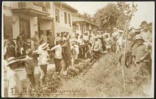 Eine Menschenkette mit Kindern und Erwachsenen in Trachtenkleidung an der Straße einer Ortschaft in Bulgarien. Zusammentreffen der bulgarischen Landbevölkerung mit uniformierten deutschen Arbeitern, die auf dem Weg zum Bau der Bagdadbahn in der Türkei sind
