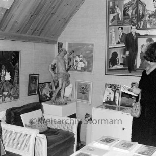 Rade: Museum Rade im Naturpark Oberalster: Ausstellung "Europas Sonntagsmaler": vorn rechts Besucherin vor Tisch mit Katalogen: links Sessel: dahinter Sockel mit Skulptur: hinten Wände mit Bildern