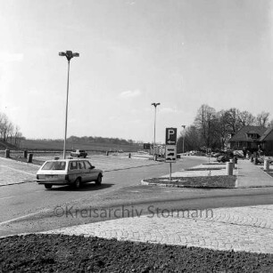A 1: Raststätte "Trave" bei Reinfeld: Modernisierung: neue Parkplätze: Mülltonnen, Straßenlampen, Autos, Verkehrsschilder: hinten rechts Gaststättengebäude