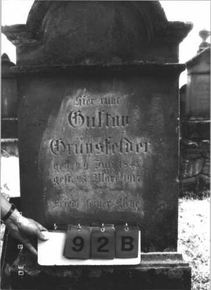 Grabstein 92 (Index: 99609728) Material: Sandstein Zustand: verwittert Maße HxBxT: 170x63x31 cm Beschreibung: Stele, eingezogener Rundbogenabschluß mit Verdachung, Mittelpalmette, Schriftfeld rechteckig eingetieft, getreppter Sockel, unten Rusticaimitat: Grabstein 92B