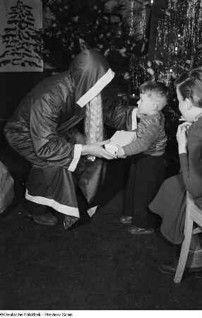 Weihnachtsmann beim Überreichen von Geschenken an Kinder auf der Weihnachtsfeier des VEB Kartographie