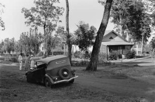 Camp von Standard Oil und Co : Blick in die Straße einer Siedlung mit Häusern, Automobil und Personen