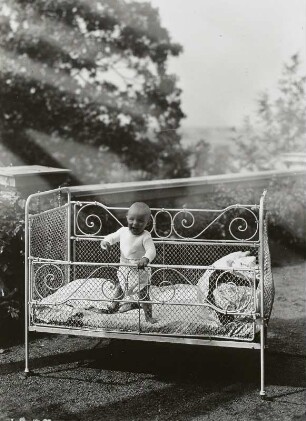 Dresden-Loschwitz. Säugling im Kinderbett, auf einer Terrasse stehend