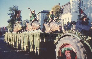 Reinfeld: Karpfenfest: Umzug: Paul-von-Schoenaich-Straße: Motto-Wagen mit Kindern auf Karpfen: vorn rechts Traktor mit Fischer: dahinter Handelsbank in Lübeck: auf der Treppe Zuschauer: hinten links Fahnenmasten, Gebäude und Bäume: 11. Oktober 1959