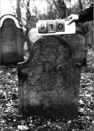 Grabstein 910 (Index: 99753225) Material: Sandstein Zustand: abgeblätt/verwitt/fast völl. Textverlust Maße HxBxT: 84x58x9 cm Beschreibung: Stele, eingezogener Rundbogenabschluß Symbolik: Löwenpaar herschauend als Schildhalter, Krone: Grabstein 910