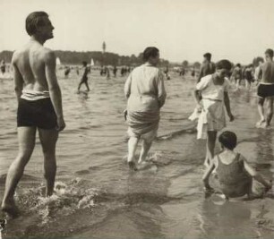 In einem Strandbad. Badegäste befinden sich am Strand und im Wasser