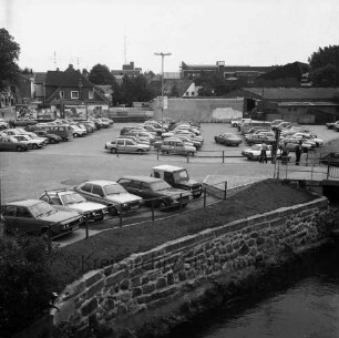 Parkplatz Heiligengeiststraße: parkende Pkw, vorne die Trave, mittig verläuft die Heiligengeiststraße, Blick Richtung Osten
