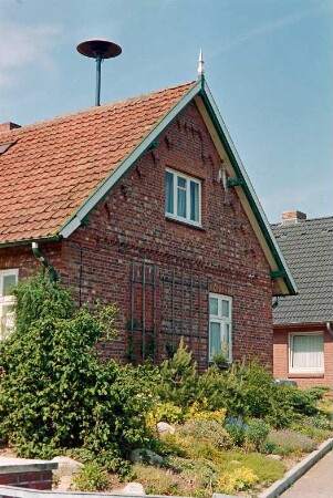Oetjendorf: Oetjendorfer Landstraße 57: traufständiges Wohnhaus aus Backstein: Giebelseite mit Backsteinzier, Rankgitter, Giebelpfahl: auf Dach Sirene: Vorgarten: hinten rechts Wohnhaus