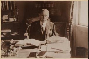Der alte Rudolf Kassner am Schreibtisch mit Büchern und Papieren
