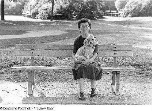 Alte Frau mit Pudel auf einer Parkbank