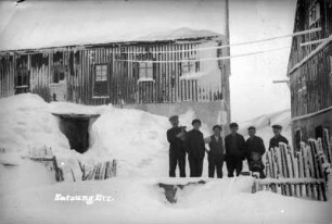 Männergruppe vor eingeschneiten Häusern