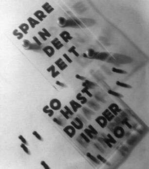 Sparen. Mit dem Spruch "Spare in der Zeit. So hast Du in der Not." beschriftete Plexiglasscheiben, auf Kugeln gelegt