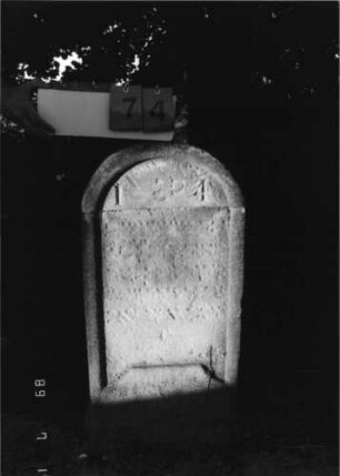 Grabstein 74 (Index: 99798181) Material: Sandstein, weiß Zustand: leicht verwittert Maße HxBxT: 83x43x9 cm Beschreibung: Stele, Rundbogenabschluß: Grabstein 74