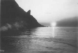 Nordkap (Norwegen). Mitternachtssonne über dem Meer vom Hochseepassagierdampfer "Victoria Luise". Blick auf Steilküste mit markanter Felsnase