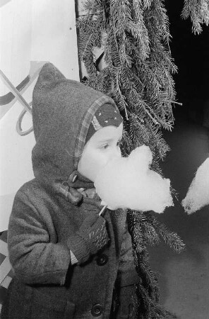 Ein Mädchen isst auf dem Weihnachtsmarkt Zuckerwatte