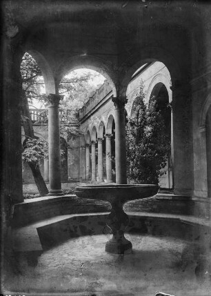 Blick über einen Schalenbrunnen auf einen Arkadenhof