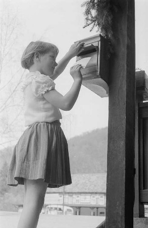 Ein Mädchen wirft Post in einen Briefkasten (in Treseburg?)