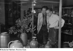 Zwei Männer betrachten die in einer Vitrine ausgestellten Vasen, Herbstmesse 1953
