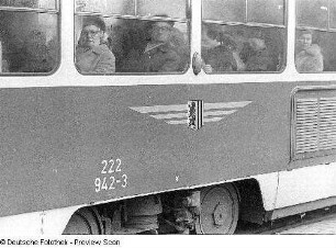 Straßenbahnfenster mit herausschauenden Fahrgästen