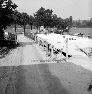 Trave: Brückenneubau: Spannbetonbrücke: Rohbau: links alte Holzbrücke: hinten Bauarbeiter und Baumaschine: dahinter Allee