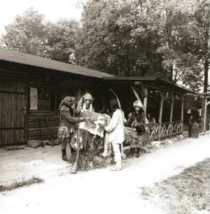 Indianistik-Gruppe des Kulturbundes der DDR, Ortsgruppe Hohenstein-Ernstthal. Gruppe in Pfadfinder- und Indianertrachten mit Scheckenfell vor einem Blockhaus